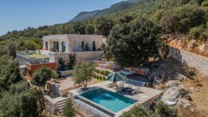 Charming stone villa with a pool surrounded by lush greenery and hills.