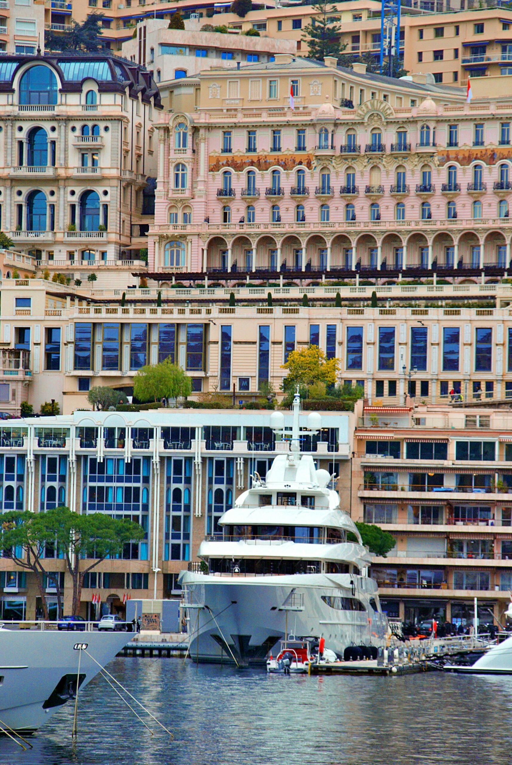 A stunning luxury yacht moored against the iconic architecture of Monaco's harbor.
