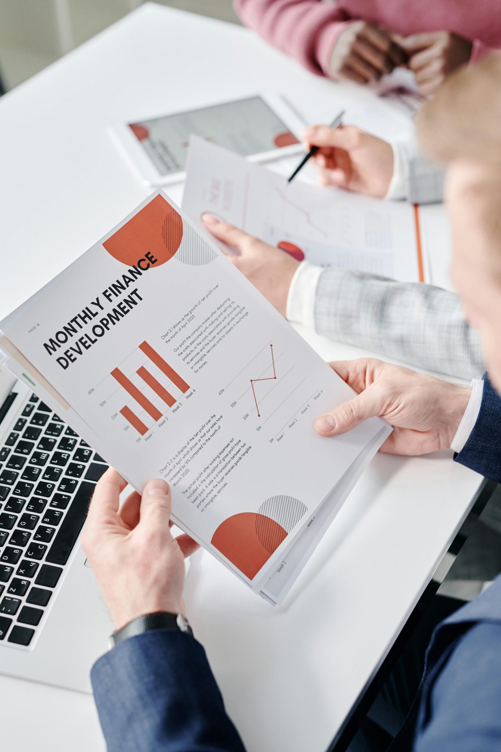 Professional setting with hands analyzing financial documents during a business meeting.